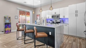 Une cuisine moderne dotée d’un îlot central, de tabourets de bar, de luminaires suspendus et d’un juke-box.