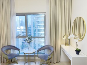 A modern room with two chairs, a small table, a mirror, and a view of a cityscape through large windows.