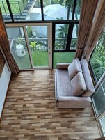Una habitación con un amplio ventanal corredera que da a un balcón con vistas a un jardín y una sombrilla blanca.