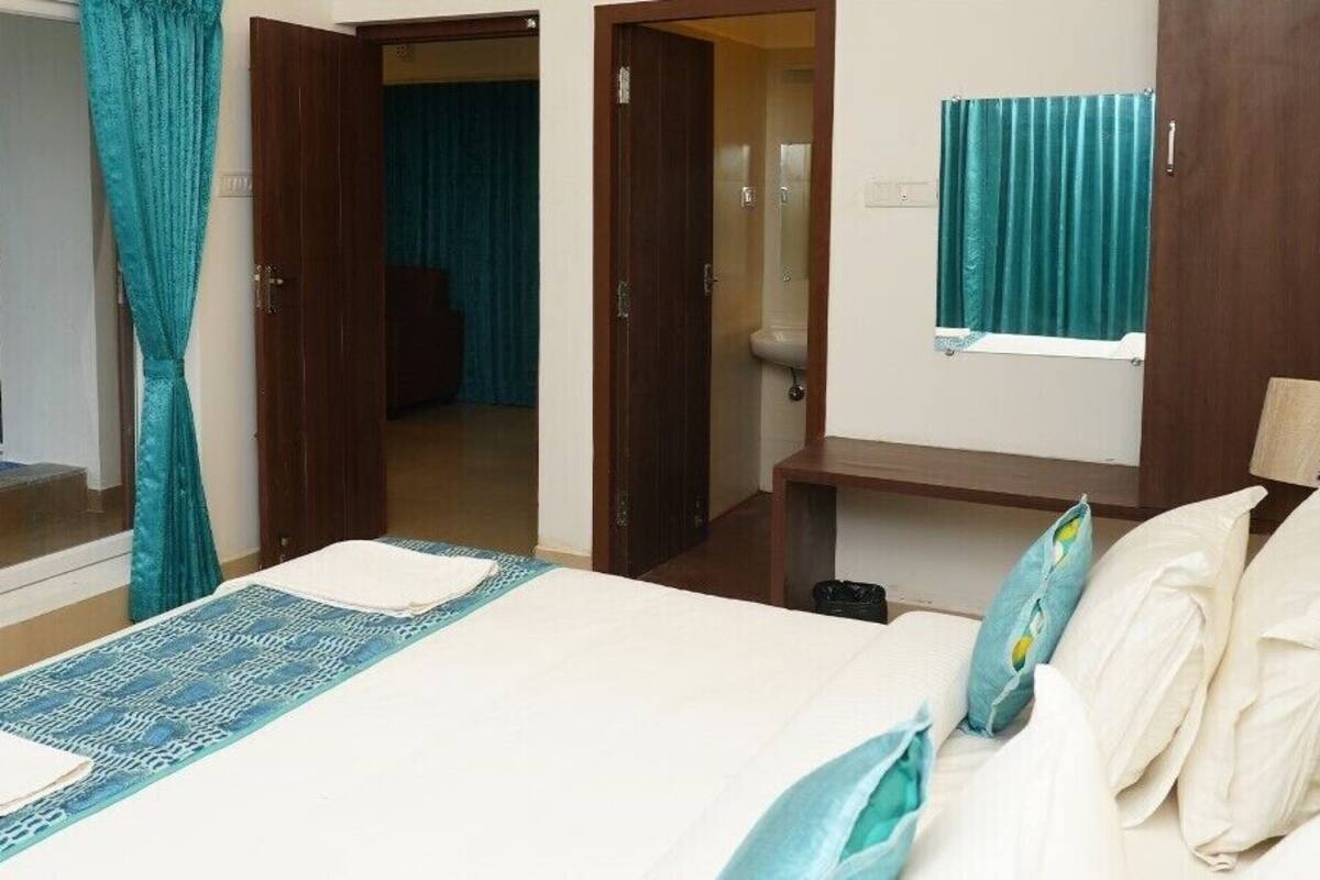 A hotel room with a bed, a small desk, a bathroom with a toilet and sink, and a shower area.