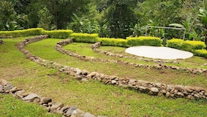 A garden with a stone pathway, neatly trimmed hedges, and a circular water feature. - Thapovan  (Kodaikanal)