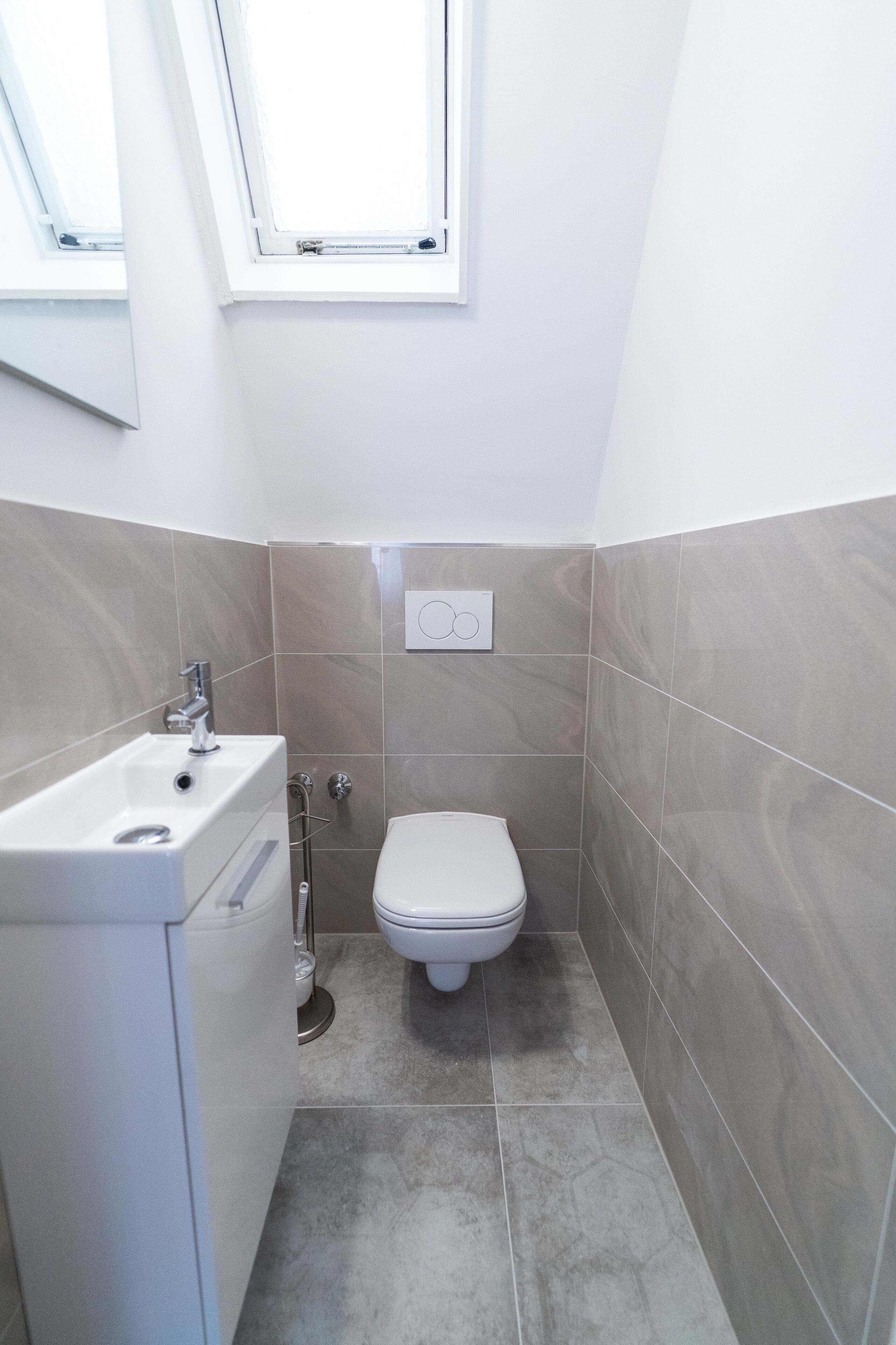 A small, modern bathroom with a toilet, sink, and shower.