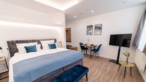 A modern hotel room with a large bed, a bench, a desk, and a TV. - Apartments am Marktplatz (Bad Urach)