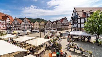 Een historisch Europees marktplein met geplaveid straatwerk, terrasjes en oude vakwerkhuizen.