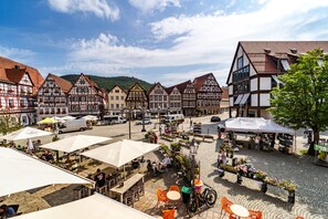 Ein traditioneller europäischer Marktplatz mit Kopfsteinpflaster, Außenbestuhlung und historischen Fachwerkhäusern.
