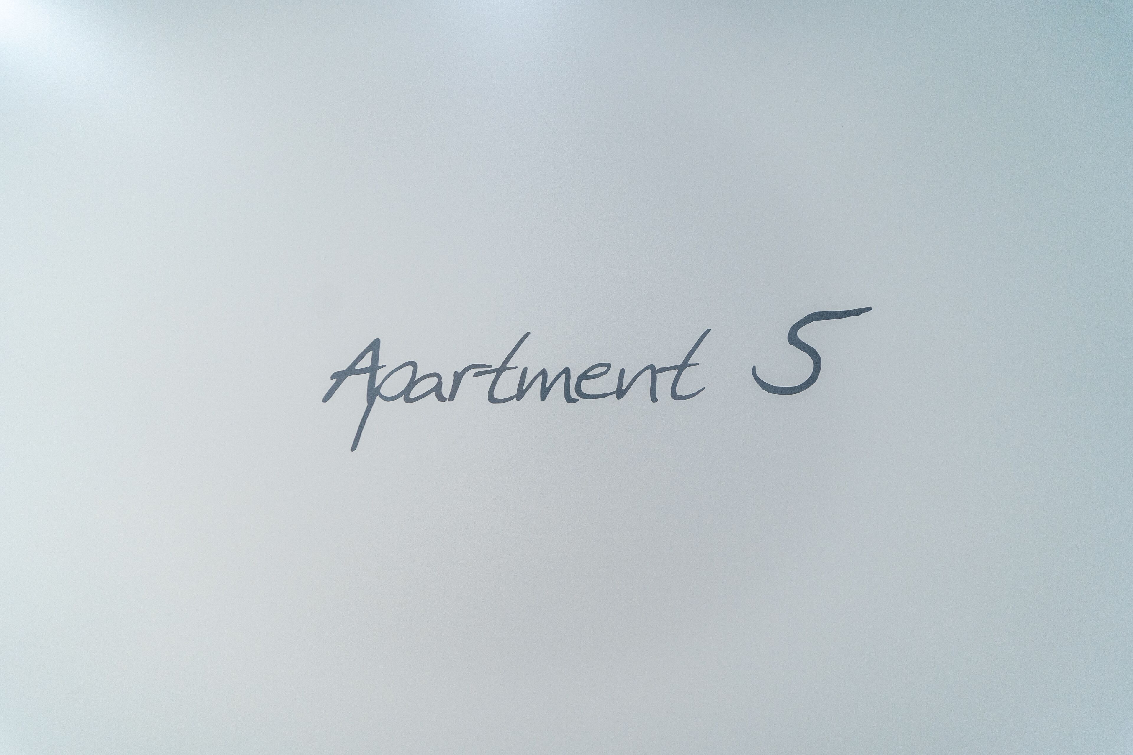Teksti ”Apartment 5” on sijoitettu yksiväriseen taustaan.