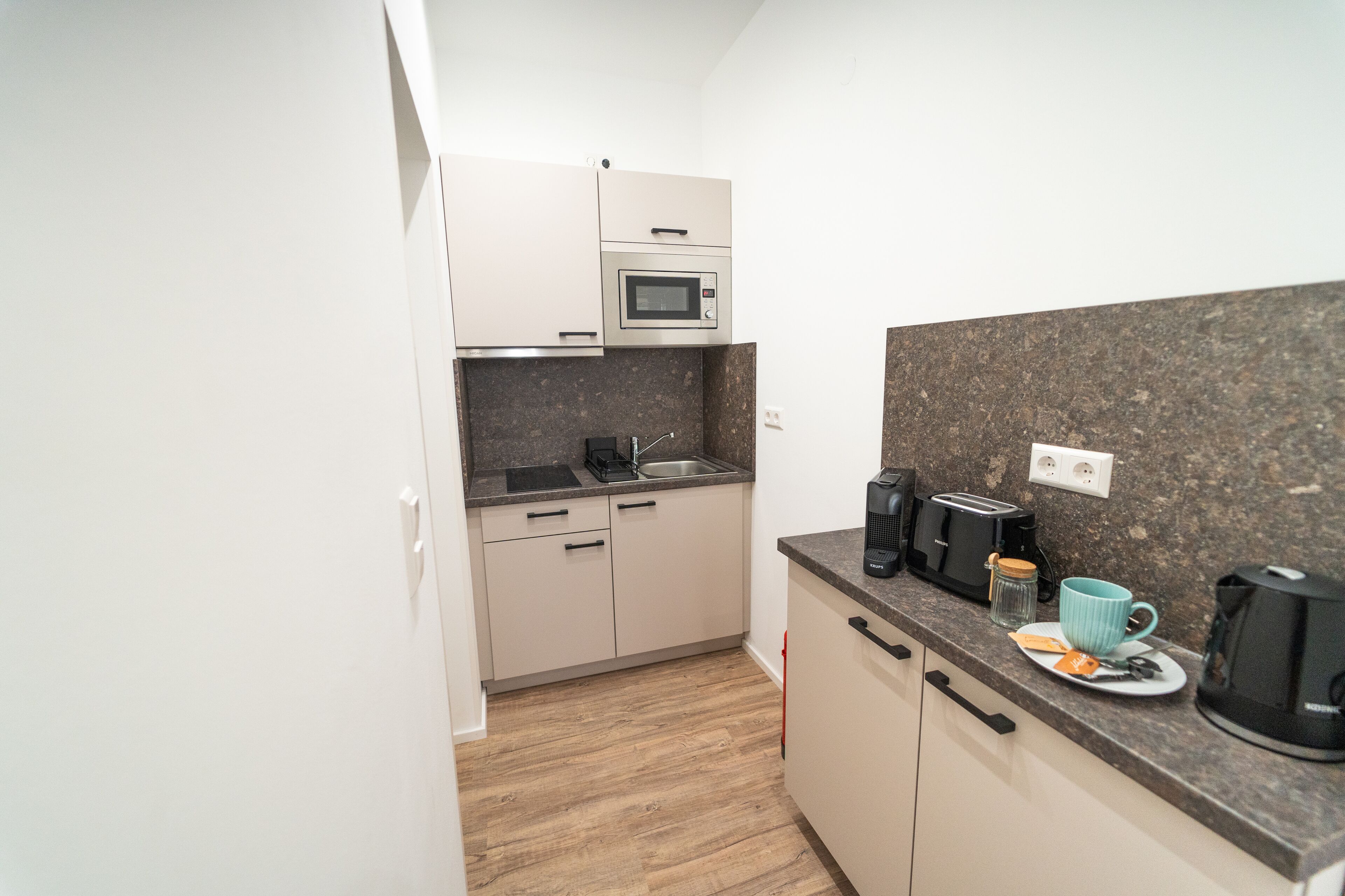 A compact kitchen with a microwave, toaster, and coffee maker on the countertop.