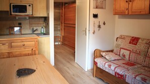 Una cocina funcional con microondas, armarios de madera, una mesa de comedor y un sofá.