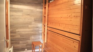 Una habitación con piso de madera, un guardarropa de madera y un taburete pequeño de madera.