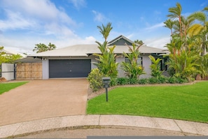 A residential house with a garage, a driveway, and a well-maintained lawn.