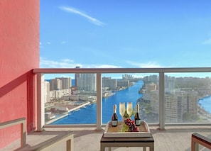 A balcony with a table set for two, overlooking a cityscape and a river.