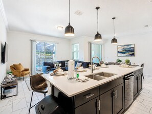 A modern kitchen with a central island, black cabinetry, and pendant lighting.