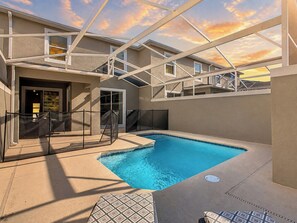 A swimming pool with a glass enclosure, surrounded by a covered patio area with seating.
