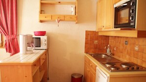 A compact kitchen with a microwave, stove, and wooden cabinets. - Gelinote Chalet for 4 People (Chatel)