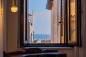 Vista a través de una ventana con el mar y edificios.