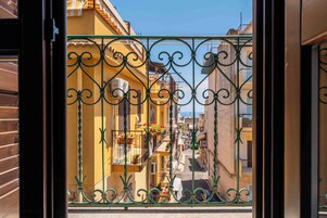 Una calle estrecha con edificios amarillos, una reja de metal y cielo despejado.