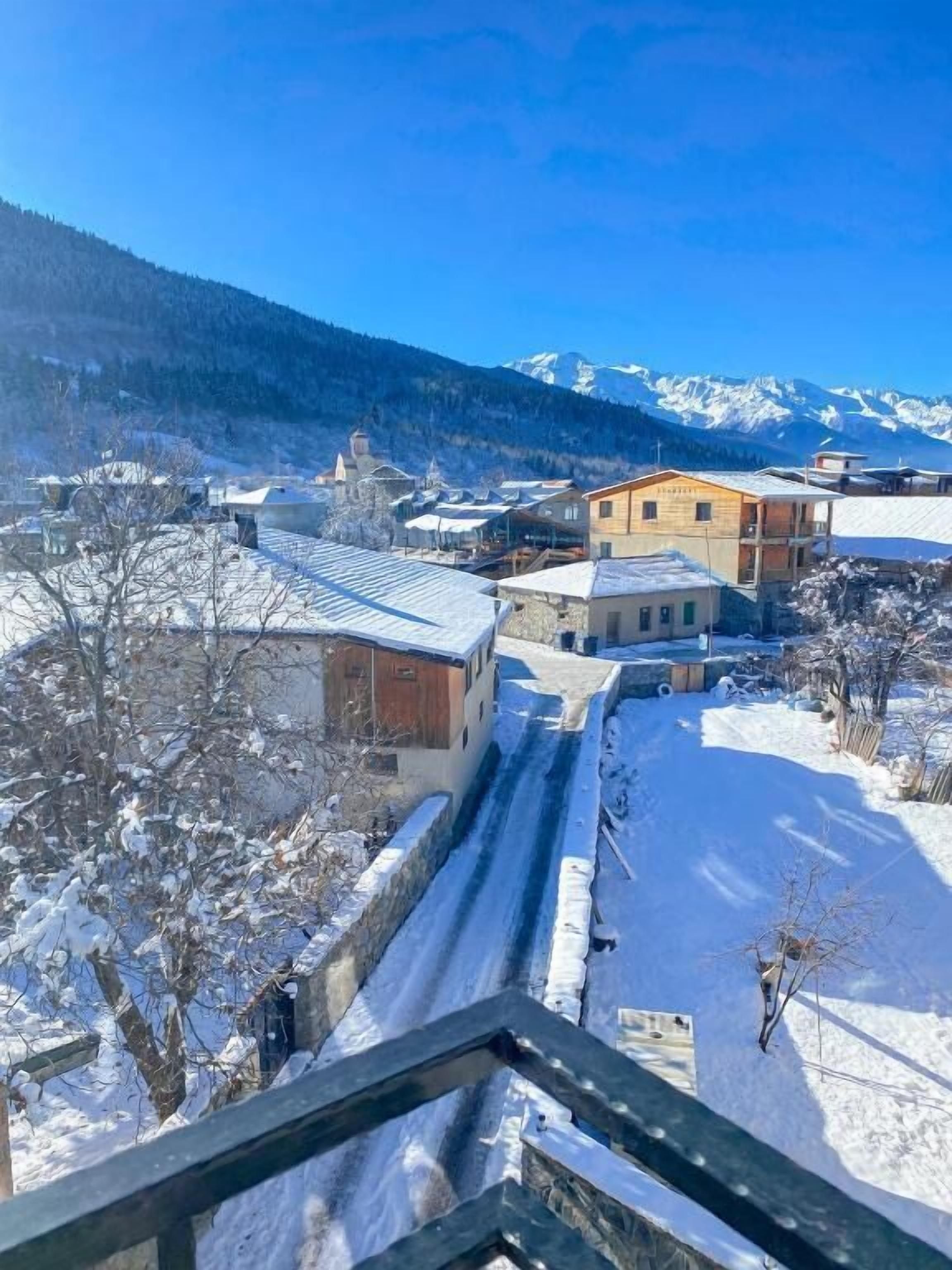 A snow-covered village with buildings and a mountain backdrop.