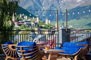 Une terrasse dotée de mobilier en bois et offrant une vue sur un village de montagne.