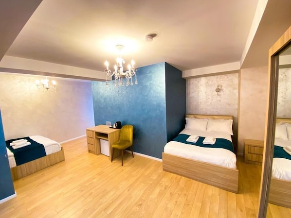 Une chambre d’hôtel moderne équipée de deux lits, d’un bureau, d’une chaise et d’un lustre.
