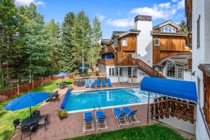 Un jardin avec une piscine, des chaises longues et une terrasse en bois.