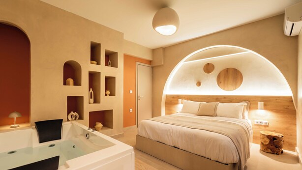 A modern bedroom with a large bed, a built-in bathtub, and a unique arched ceiling design. - Gaia Nest 1-bedroom apartment in Piraeus (Pireas)