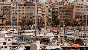 A marina with boats docked, surrounded by multi-story buildings. - Gaia Nest 1-bedroom apartment in Piraeus (Pireas)