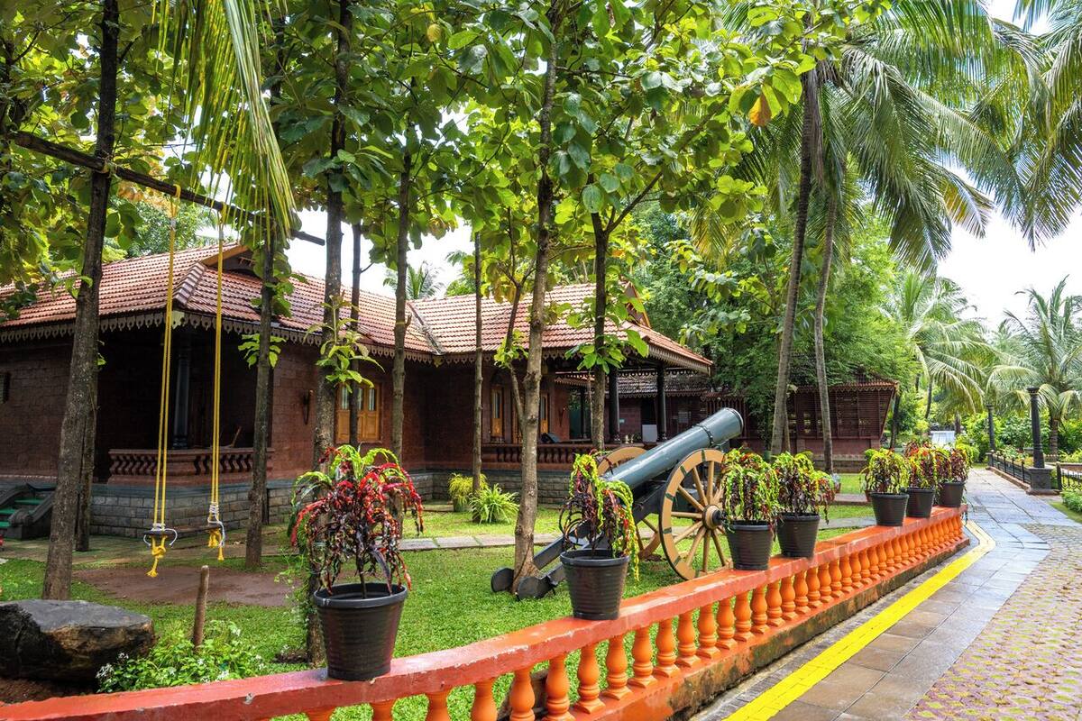 A traditional building with a tiled roof, surrounded by lush greenery and potted plants.