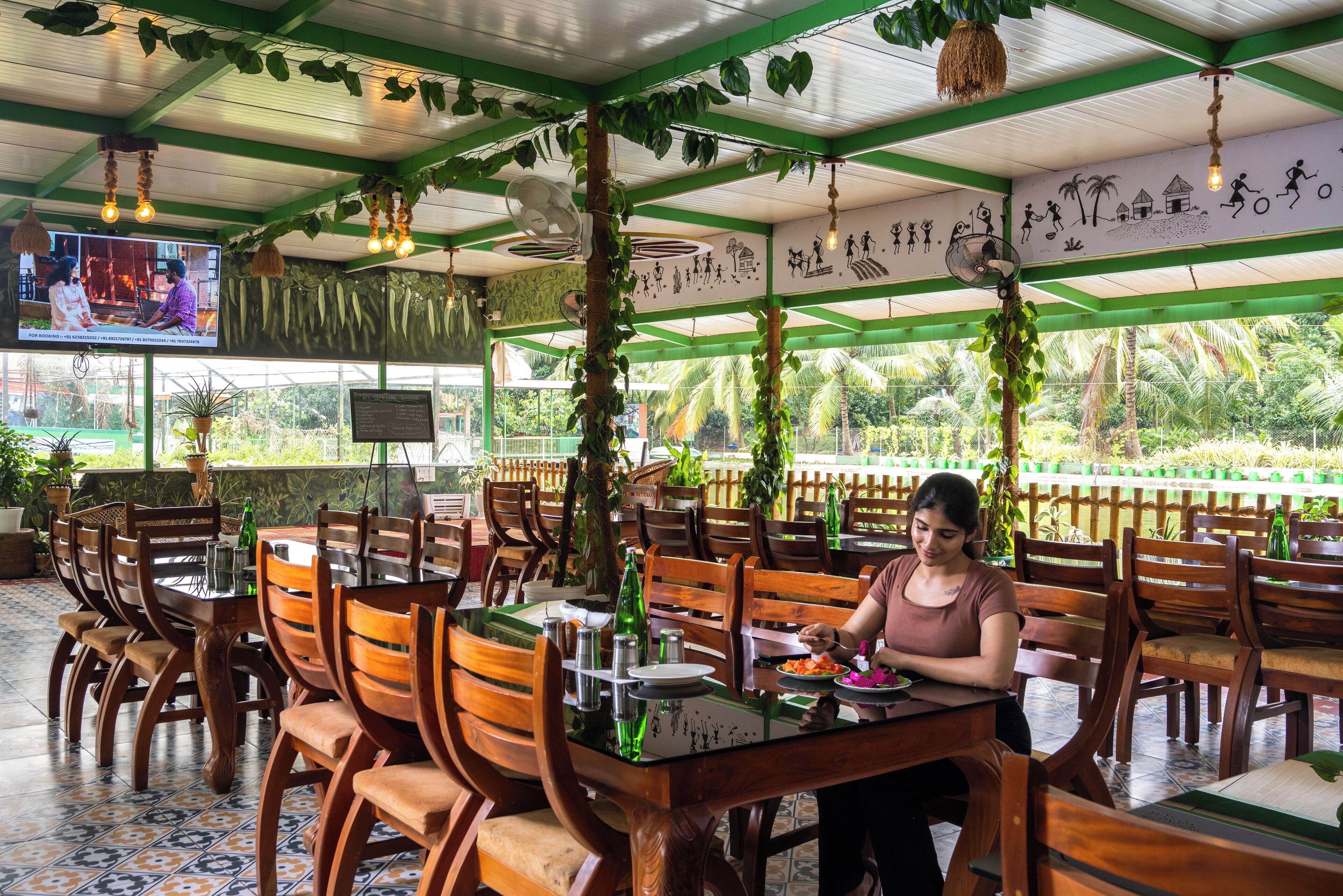 Un restaurante con mesas y sillas de madera, una pantalla de televisión y una pizarra de menú.
