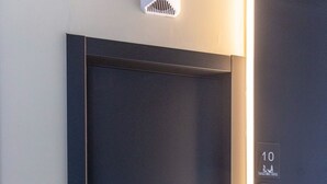 Ingresso di un hotel con una porta scura, un tappetino d'ingresso e un lampadario sopra la porta.