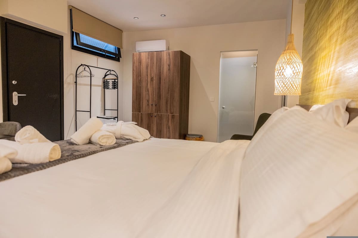 Une chambre d’hôtel comprenant un lit, une armoire, un miroir, un porte-serviettes et un luminaire suspendu.