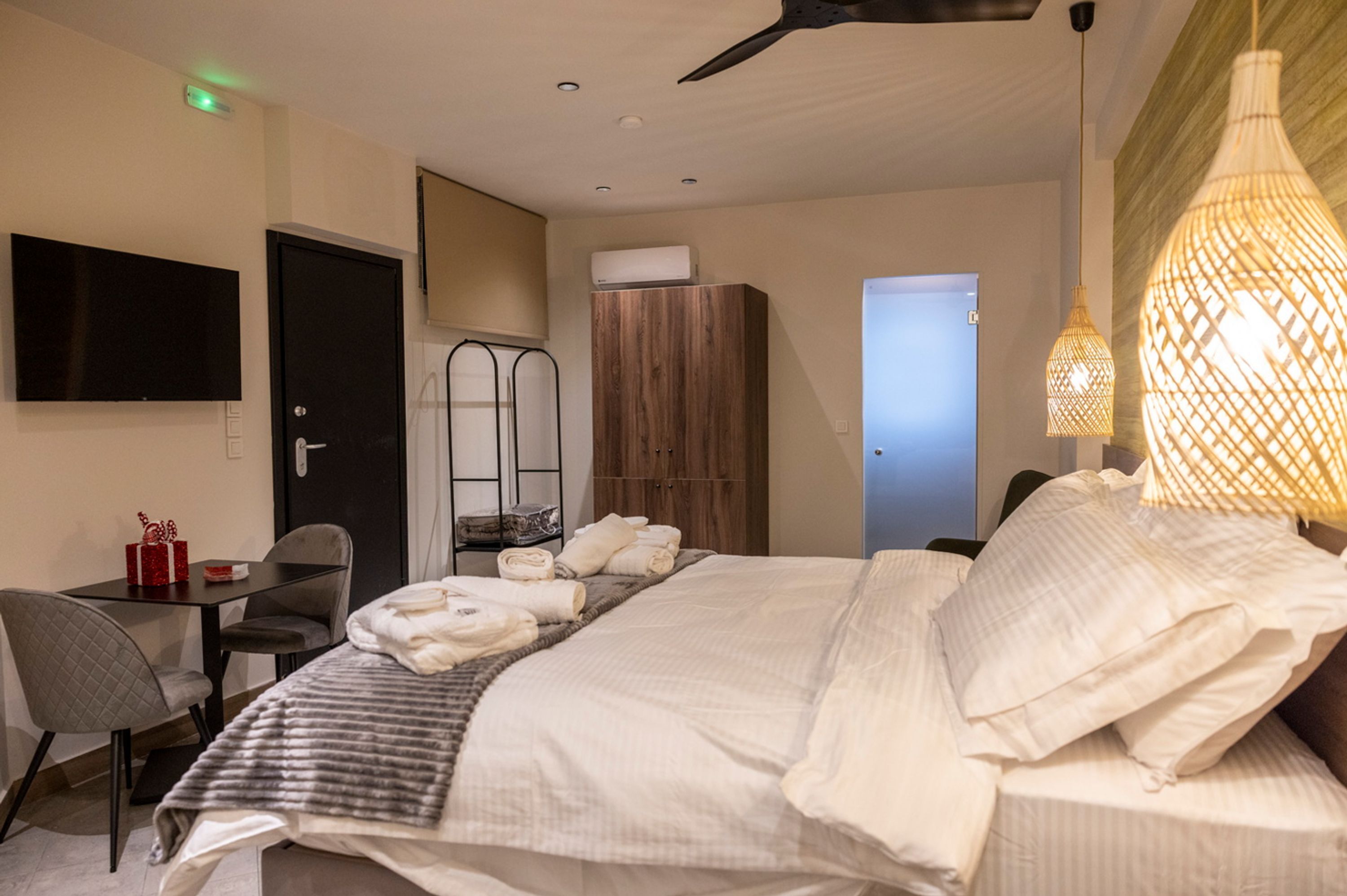 Une chambre d’hôtel équipée d’un lit, d’un bureau, d’une chaise, d’une télévision et d’un ventilateur de plafond.