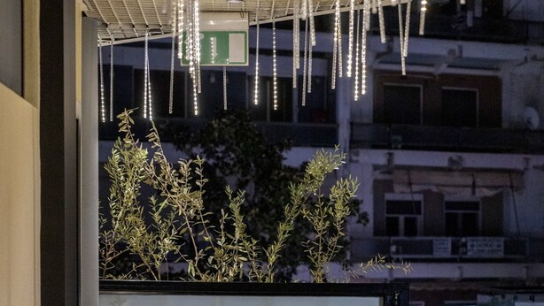 Segnaletica per Trikala Mall Suites con balcone e luci appese.