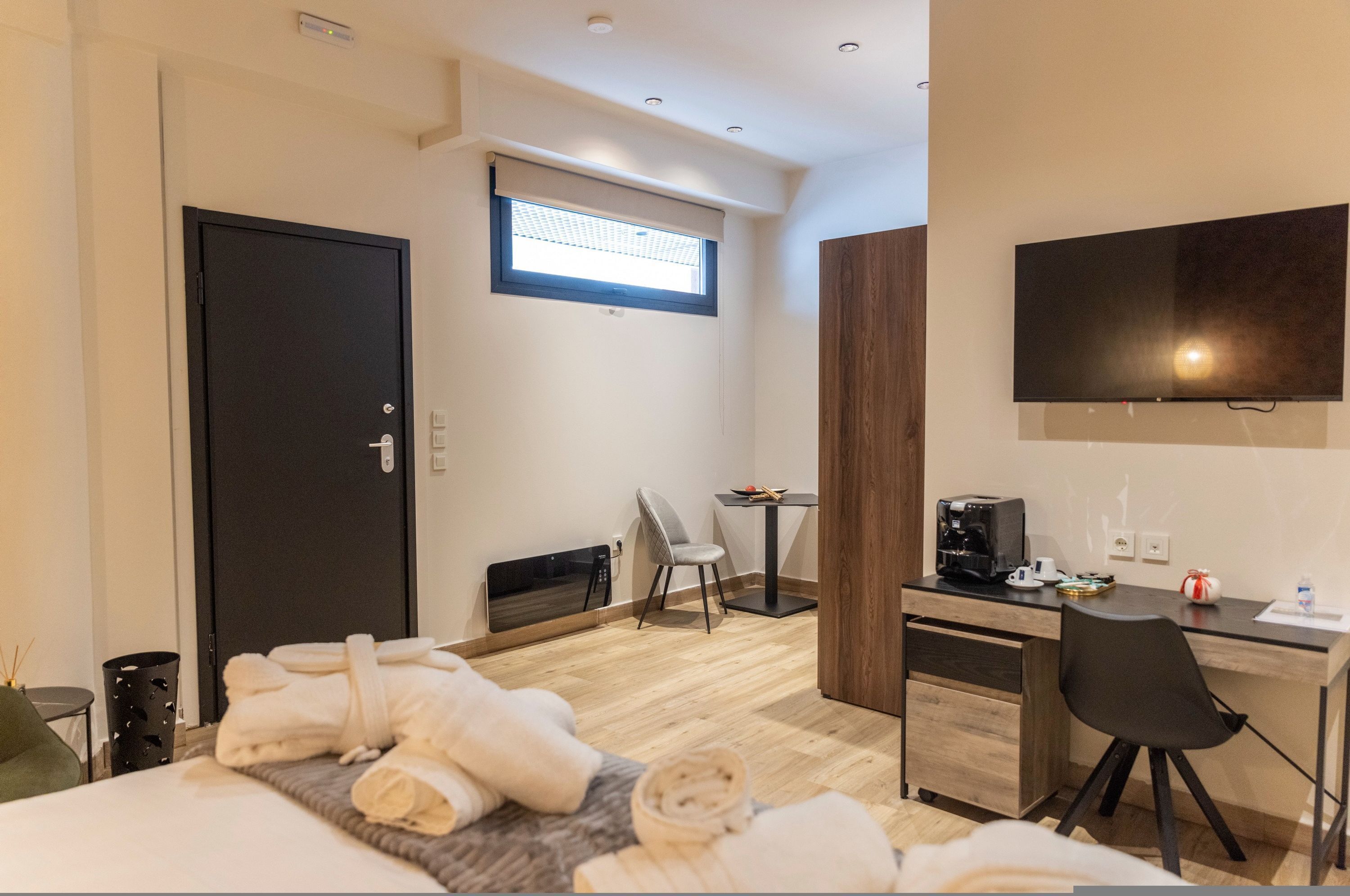 A modern hotel room with a bed, a desk, a chair, a TV, and a window.