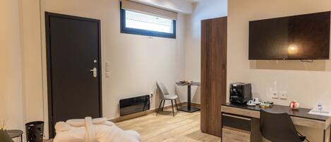 A modern hotel room with a bed, a desk, a chair, a TV, and a window.