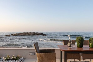 A seaside terrace with wicker chairs and a table, overlooking the ocean and rocky outcrops. - Villa Seashell★ Luxurious villa right on the beach in Chania (Galatas)