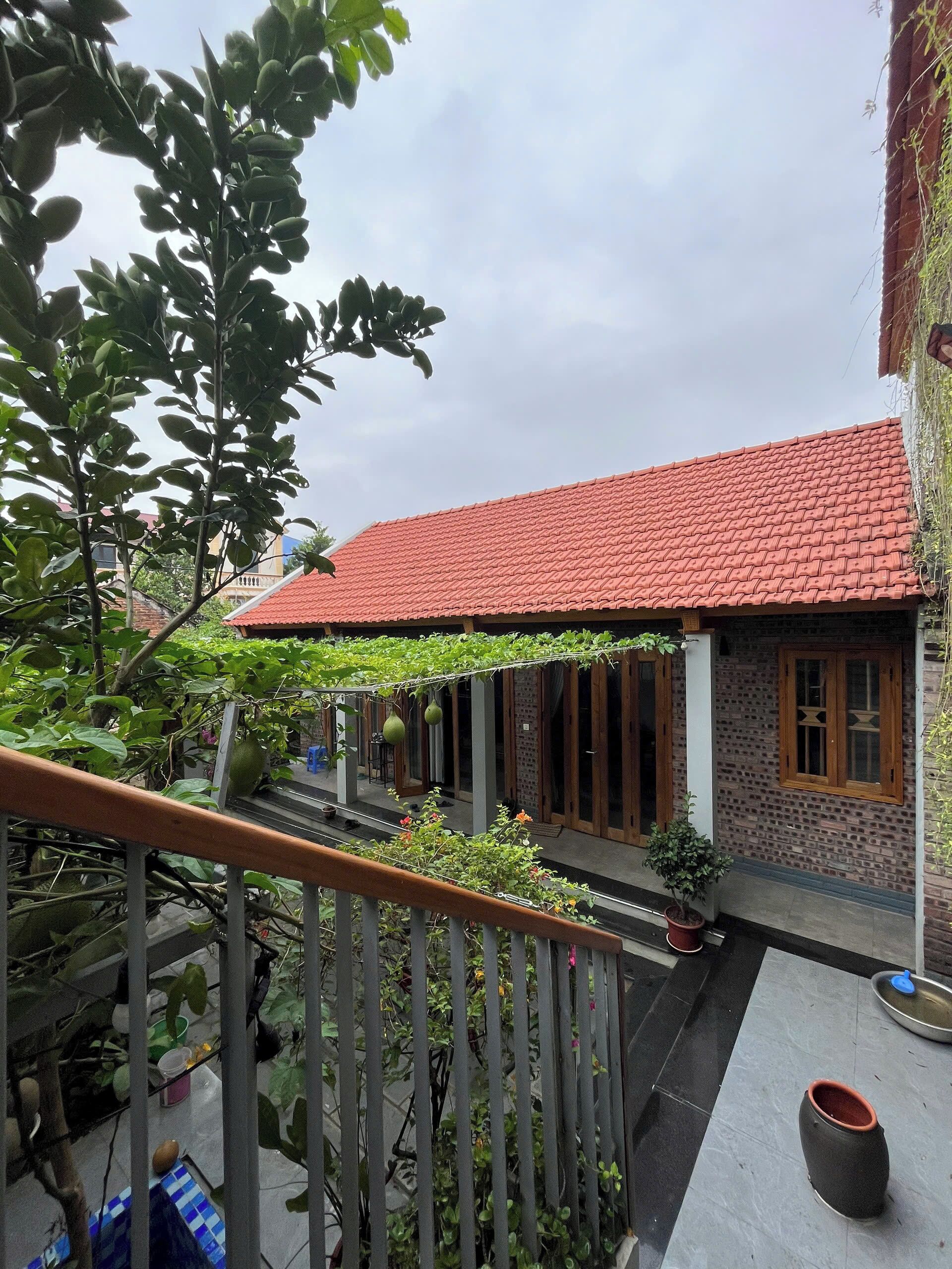A building with a red-tiled roof, a balcony with a railing, and potted plants.