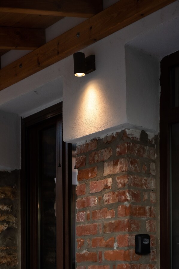 A brick wall with a recessed light fixture and a door frame. - The Lake House Angeliki (Rigas Feraios)