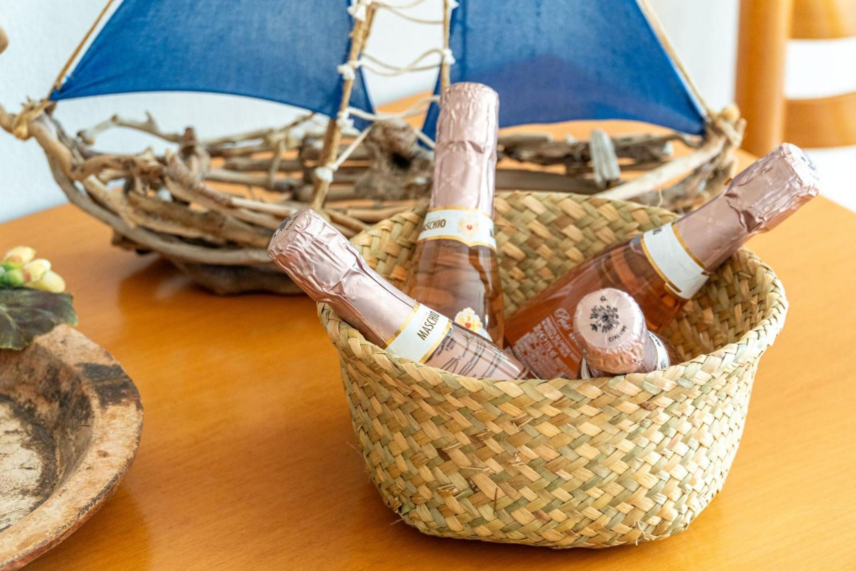 A woven basket containing two bottles of champagne on a wooden table.
