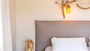 A bedroom with a large bed, a bedside table with a lantern, and a wall-mounted light fixture. - Paxi Apt in Gaios With 1 Bedrooms and 1 Bathrooms (Paxos)