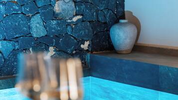 A stone wall, a vase, and a dining table with a glass and a plate.