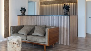Un soggiorno moderno con un divano grigio, un tavolino in legno e un pannello decorativo in legno con due busti.
