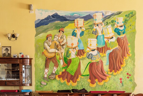 A mural of people in traditional attire carrying baskets, set against a mountainous landscape. - Agriturismo nel cuore del Pollino con Vista Panoramica (Plataci)