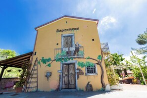 A building with a yellow facade, a wooden door, and a balcony with a railing. - Agriturismo Radici Irpine (Rocca San Felice)