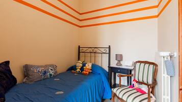 Een slaapkamer met een bed, een stoel, een nachtkastje en een dressoir.