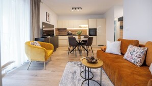 Un salon moderne comprenant un canapé, un fauteuil jaune, une table basse et un coin repas avec une table et des chaises.