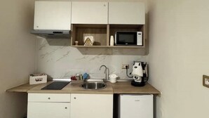Eine kleine Küche mit Mikrowelle, Kaffeemaschine und einem Kühlschrank.