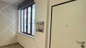 Ein Flur mit Fenster, einer Tür und einem Gemälde an der Wand.