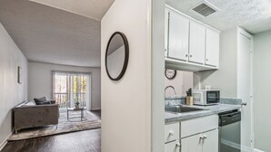 Une cuisine moderne avec des meubles blancs, un four à micro-ondes et un lave-vaisselle.