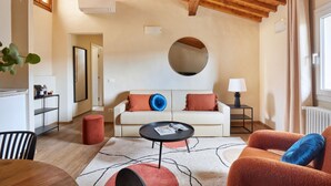 A living room with a sofa, round coffee table, and a red ottoman. - Casa Negroni, ancient house in front of medieval walls (Firenze)