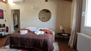 A bedroom with a bed, a round mirror, a bedside table with a lamp, and a radiator. - Casa Negroni, ancient house in front of medieval walls (Firenze)